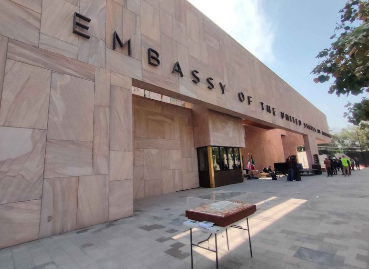 A modern stone‑faced building displays “Embassy of the United States of America” in large black letters above its entrance.