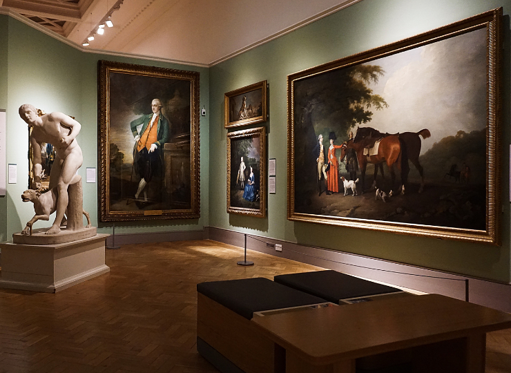 An art gallery room displays large classical paintings on green walls alongside a marble sculpture in the foreground.