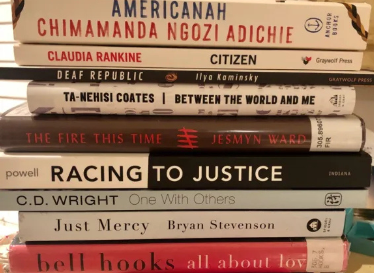 A horizontal stack of books shows nine colorful spines featuring well‑known contemporary titles on race, justice, identity, and love.
